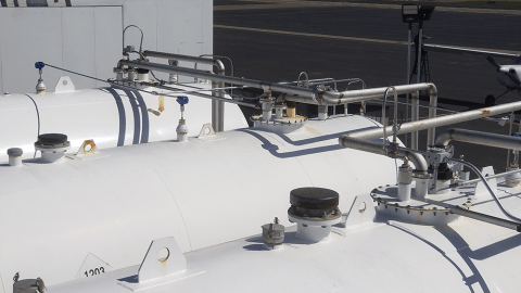 Three large white fuel tanks being monitored by a ControlByWeb device