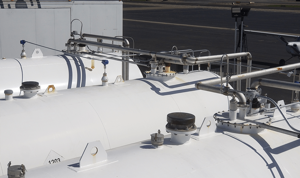 Three large white fuel tanks being monitored by a ControlByWeb device