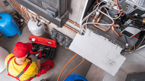 Commercial heating technician working on an IoT application with a commercial heater