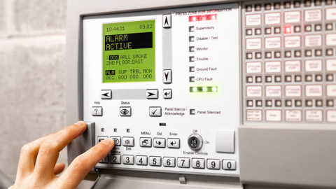 Photograph of an alarm panel. Alarm shows as active with smoke detector connected.
